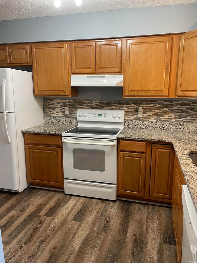 Kitchen with white appliances, dark hardwood / woo