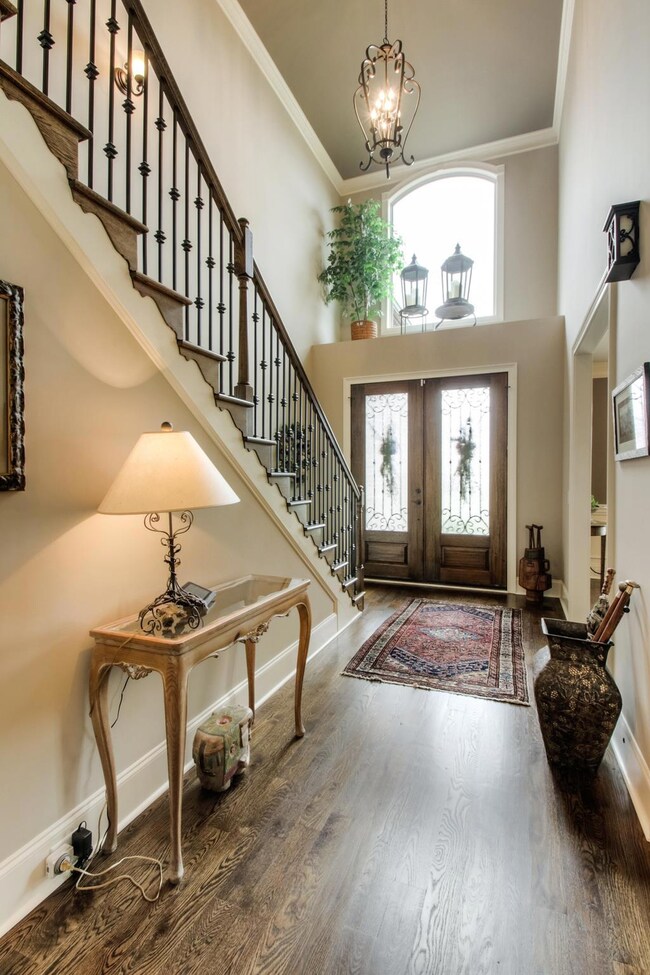Gleaming hardwoods and wrought iron staircase in the light filled two story foyer.