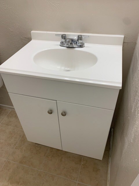 Bathroom with vanity, a textured wall, and light tile patterned flooring