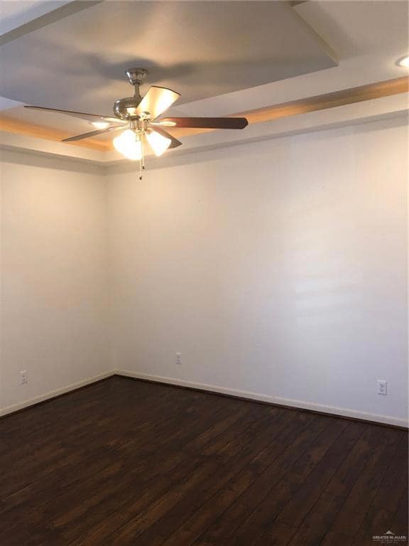 Spare room featuring ceiling fan, baseboards, a raised ceiling, dark wood-style floors, and recessed lighting