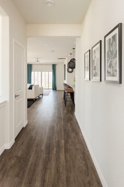 Corridor with dark wood-style flooring and baseboards