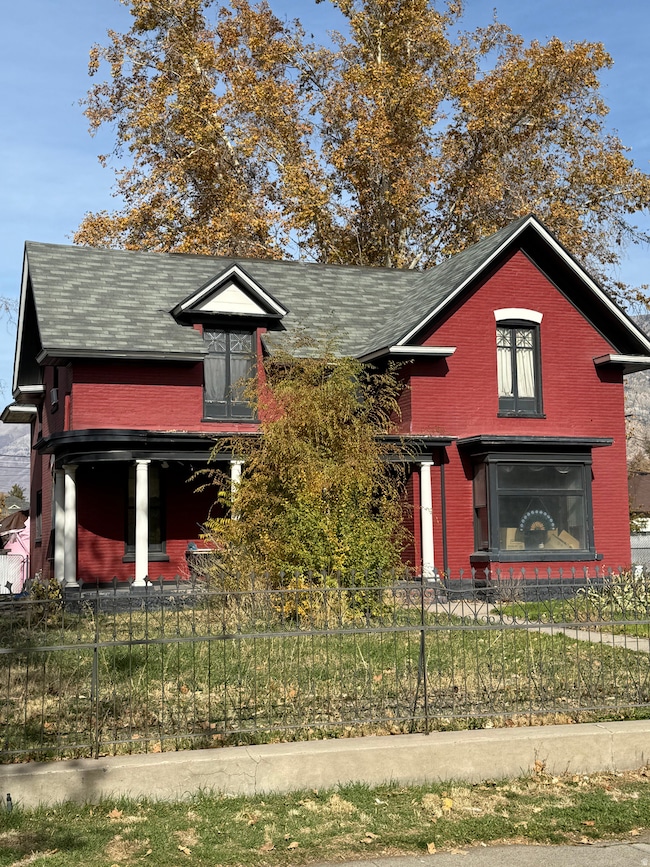 View of front of house with brick siding, a fenced front yard, and a shingled roof