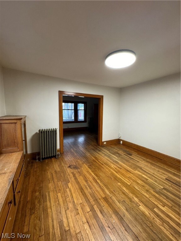 Unfurnished room featuring radiator and dark wood-type flooring