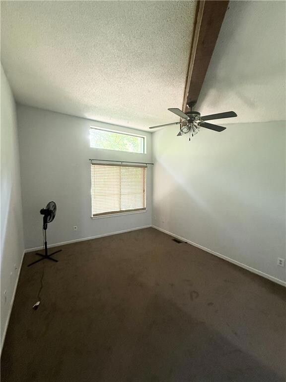 Carpeted empty room with a ceiling fan, a textured