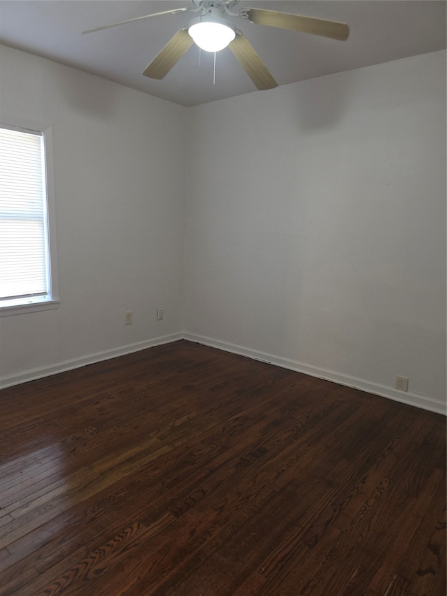Unfurnished room with dark wood-style flooring and ceiling fan