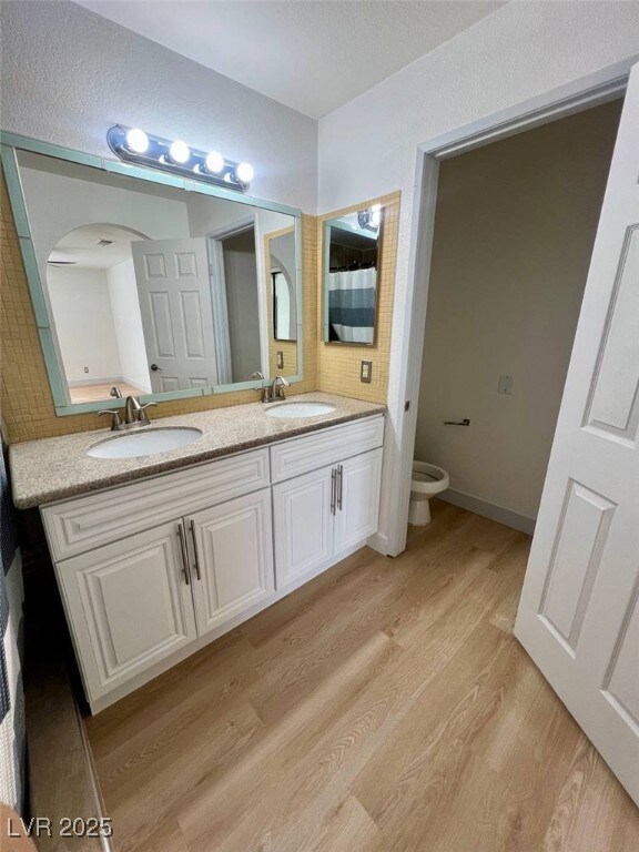 Bathroom with double vanity, toilet, a sink, and w