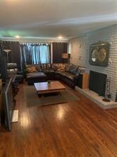 Living room featuring brick wall, a fireplace, and hardwood / wood-style flooring