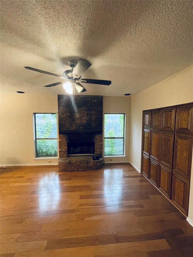 Unfurnished living room with ceiling fan, a brick 