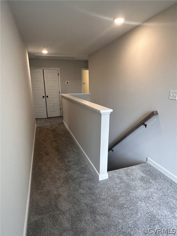 Hallway featuring dark colored carpet