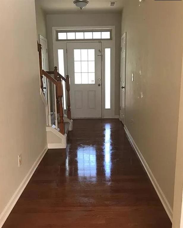 Entryway featuring stairway, baseboards, wood finished floors, and visible vents