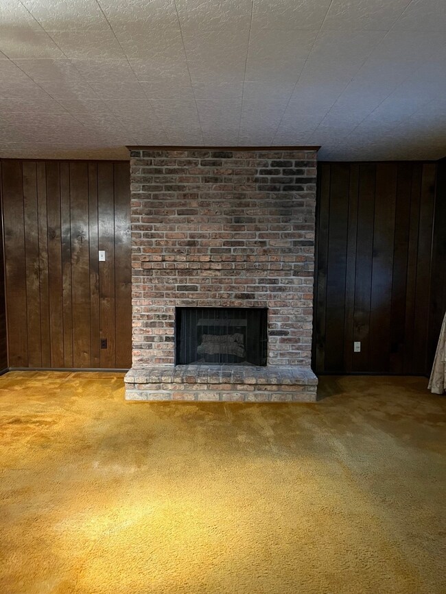 Cozy room featuring a classic brick fireplace, dar