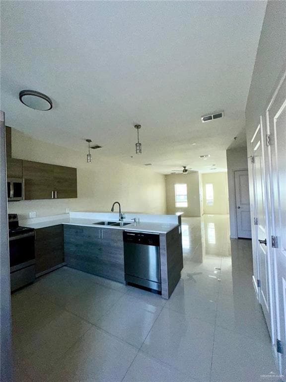 Kitchen with modern cabinets, stainless steel appliances, a peninsula, and light tile patterned floors