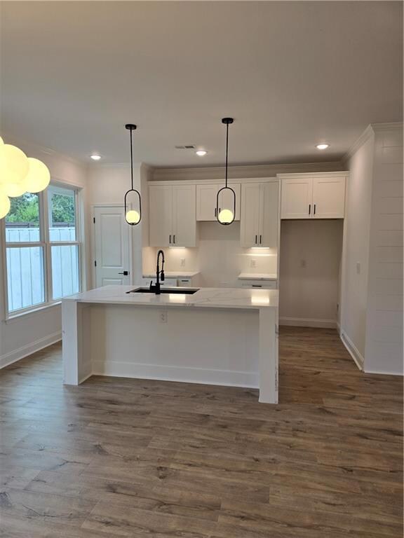 Kitchen with white cabinets, light stone countertops, a kitchen breakfast bar, dark wood-type flooring, and decorative light fixtures
