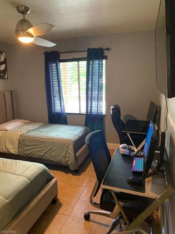 Bedroom with light tile patterned floors, a textured ceiling, ceiling fan, and a desk