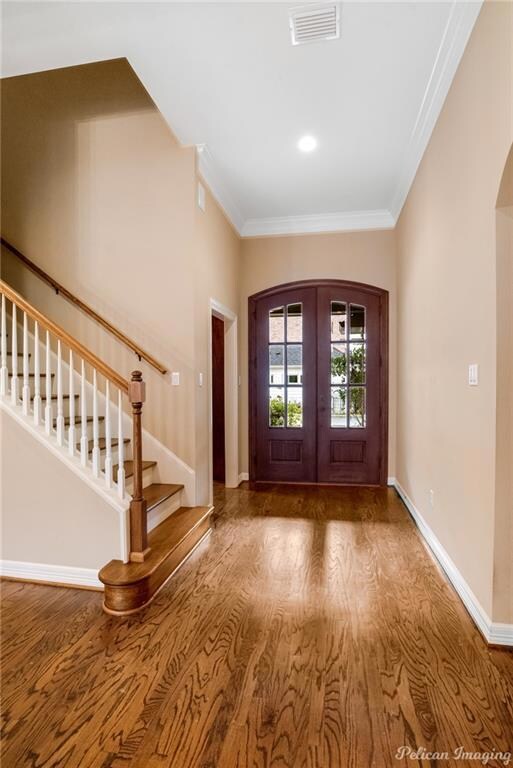 Foyer with wood floors, tall ceilings and crown mo