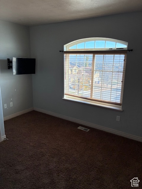 Empty room featuring dark carpet