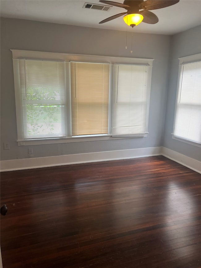 Unfurnished room featuring dark wood-style floors and a ceiling fan