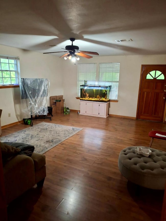 Living area with baseboards, ceiling fan, wood fi