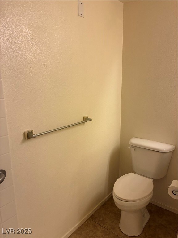 Bathroom featuring toilet and dark tile patterned floors