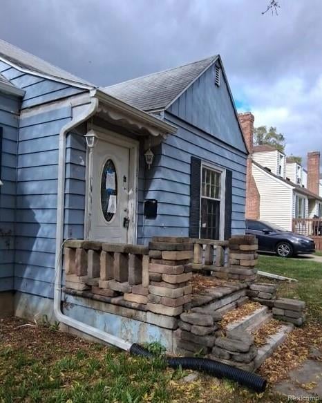 Doorway to property with roof with shingles