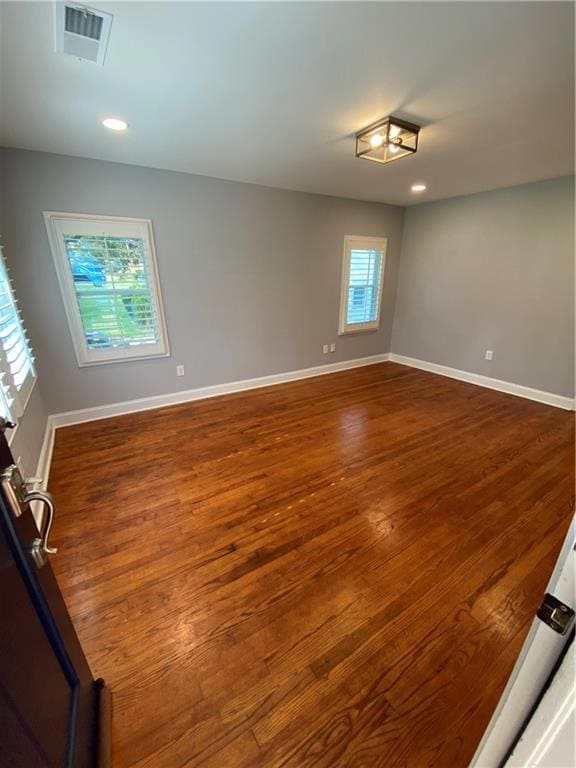 Empty room with dark wood-type flooring, recessed lighting, and baseboards