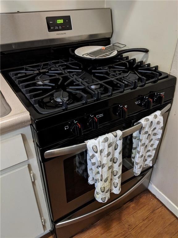 Kitchen view of gas stove, wood finished floors, 