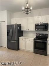Kitchen with black appliances, a chandelier, light