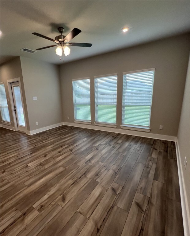 Unfurnished room featuring ceiling fan and dark wo