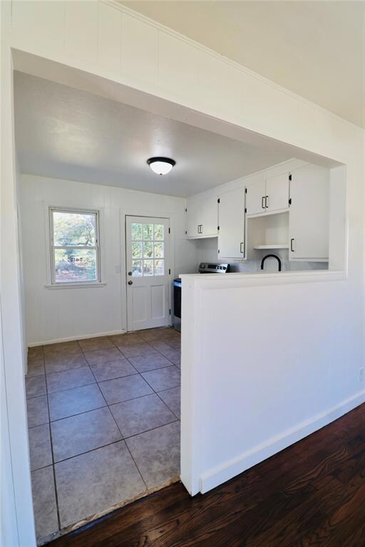 Kitchen with white cabinetry, electric range, light countertops, dark wood-style flooring, and a peninsula