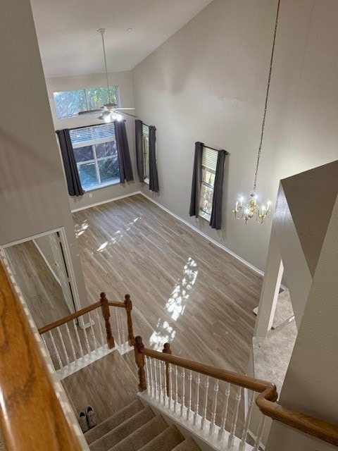 Stairway featuring high vaulted ceiling, wood finished floors, healthy amount of natural light, and a chandelier