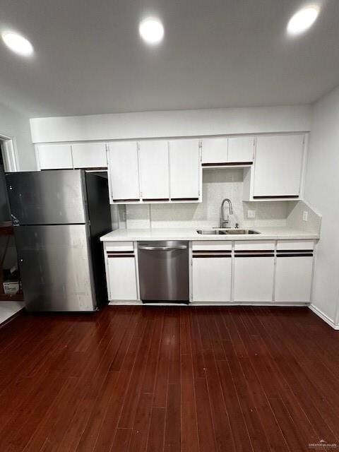 Kitchen featuring dark wood-type flooring, dishwasher, white cabinets, sink, and fridge