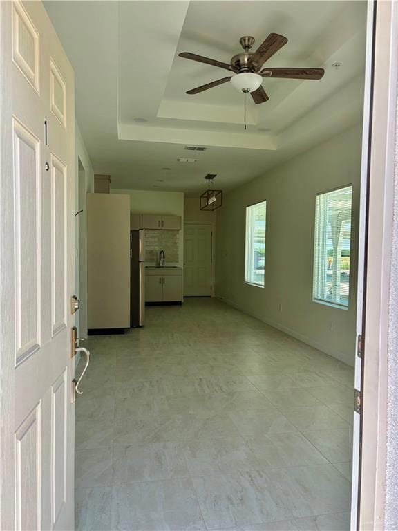 Unfurnished room featuring a raised ceiling and ceiling fan
