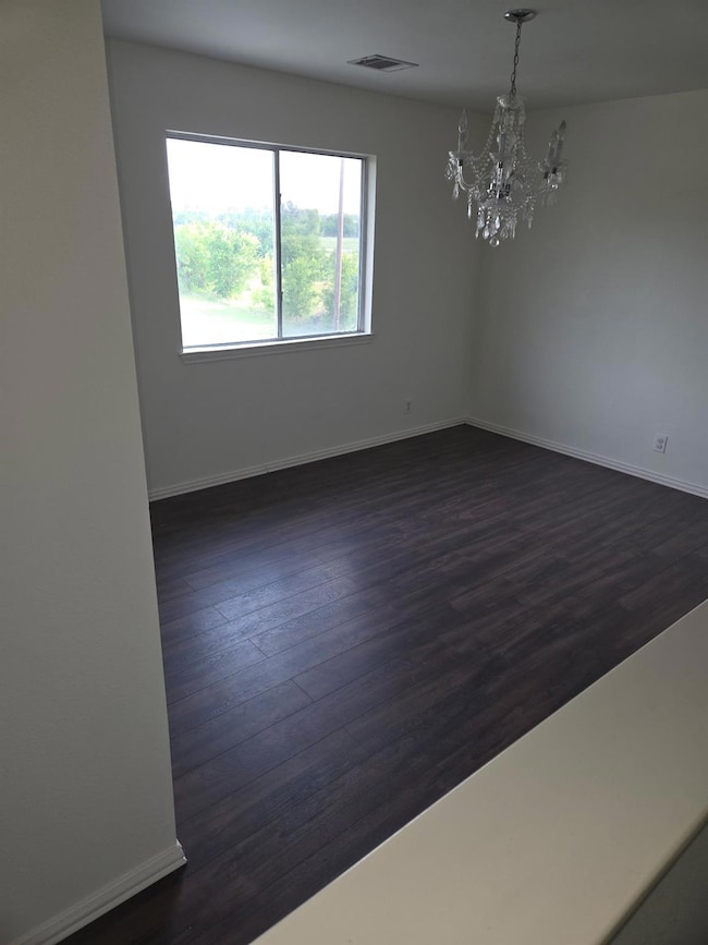 Spare room featuring a chandelier, baseboards, an