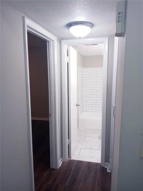 Hallway featuring a textured ceiling and dark hard