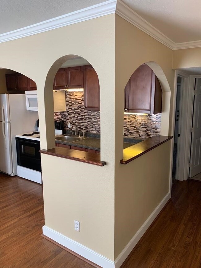 Kitchen featuring crown molding, dark wood-style floors, range with electric cooktop, tasteful backsplash, and white microwave