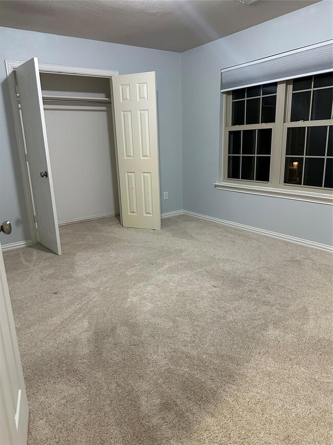 Bedroom with a closet, light carpet, and baseboard