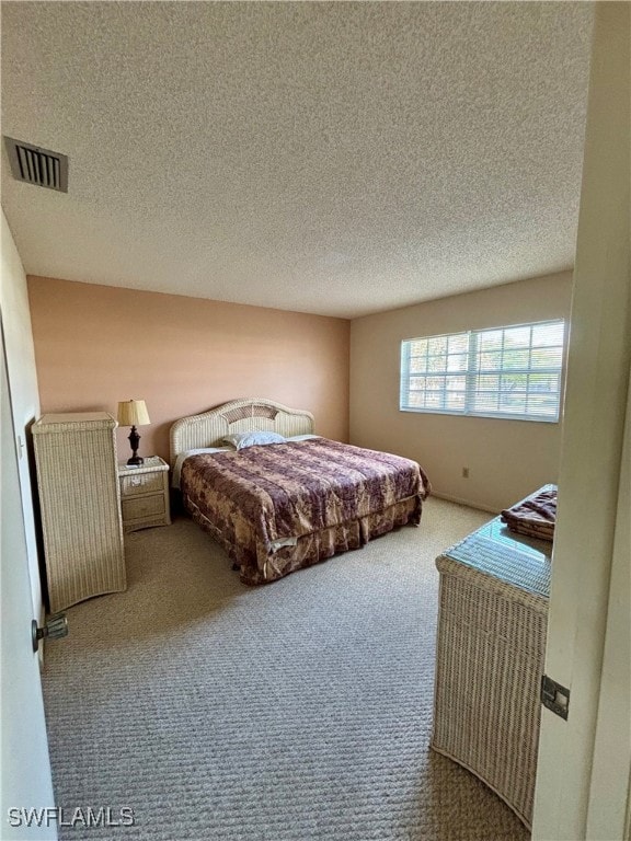 Bedroom with a textured ceiling, carpet flooring,