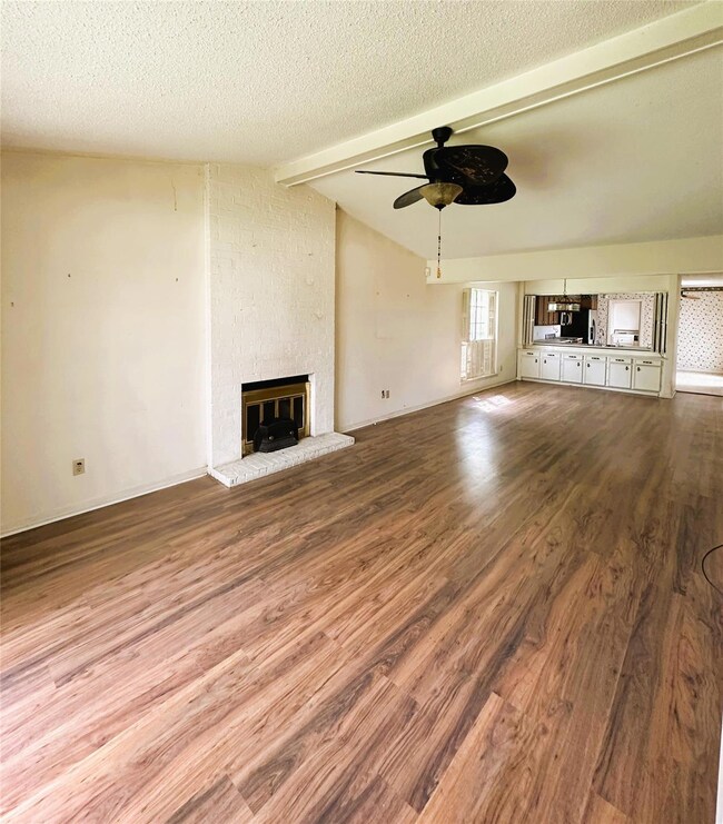 Unfurnished living room featuring ceiling fan, a t