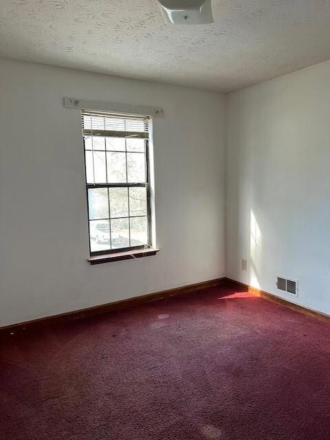 Empty room with a textured ceiling, baseboards, vi