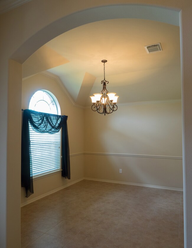 Archway from the entry, interesting angles of the ceiling, great natural light from the decorative window, and a chandelier accent this dining room at the front of the house just off the main entry.