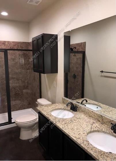 Bathroom featuring a stall shower, double vanity, and recessed lighting