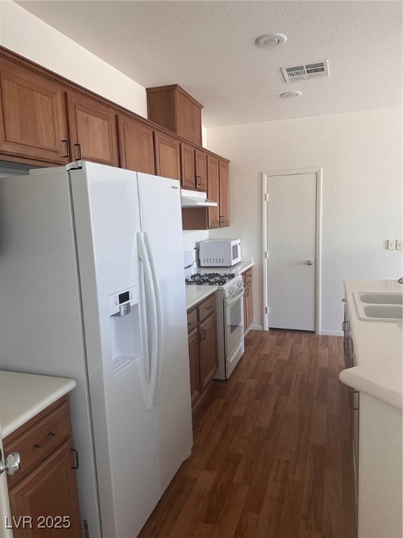 Kitchen featuring a sink, fridge, dark wood-type f
