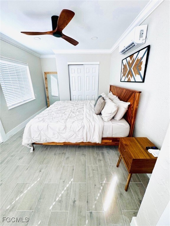 Bedroom with wood finish floors, a closet, ornamental molding, a ceiling fan, and a wall mounted AC