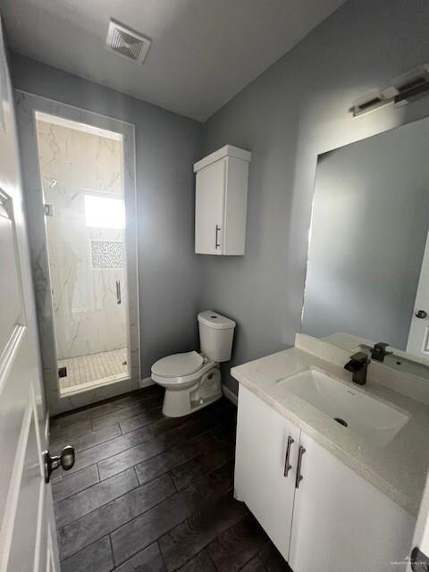 Bathroom featuring hardwood / wood-style flooring, vanity, toilet, and walk in shower