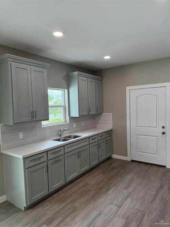Kitchen featuring gray cabinets, light wood-style floors, light countertops, backsplash, and recessed lighting