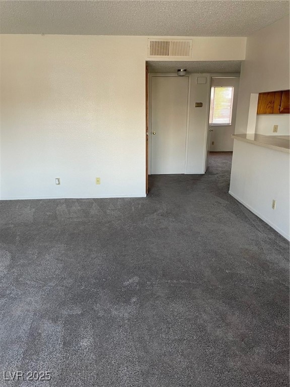 Spare room with dark colored carpet and a textured ceiling