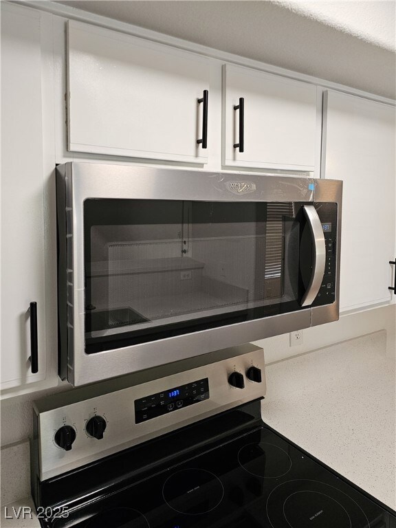 Kitchen view of stainless steel appliances and white cabinets