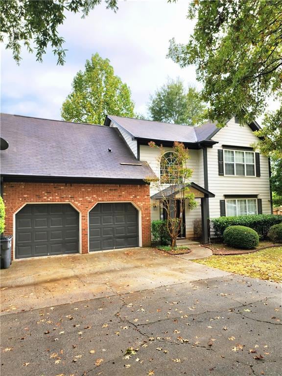 View of front of property featuring concrete driveway, a garage, and brick siding
