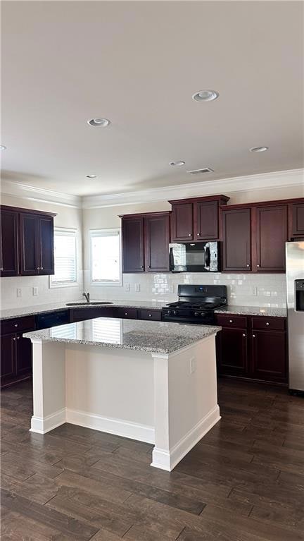 Kitchen with black appliances, crown molding, a kitchen island, backsplash, and light stone countertops