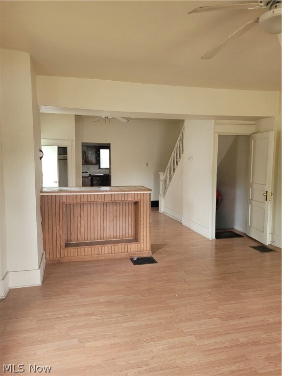 Unfurnished living room featuring ceiling fan and light wood-type flooring